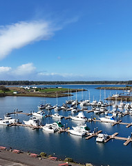 Boats docked at the marina at Salmon Harbor, blue water and blue skies in Winchester Bay
