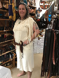 Woman wearing light-colored handmade deerskin dress with leather knife holster at Four Winds Leather Shop