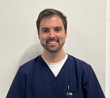 Smiling NeuroSPARK therapist wearing navy scrubs, standing against a light background
