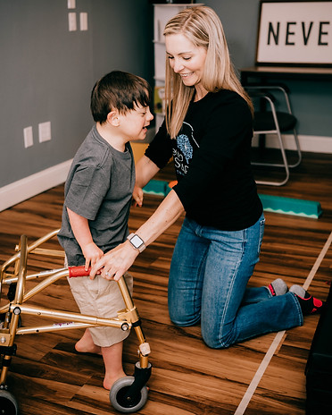 Therapist at NeuroSPARK supports a young child using a walker during a pediatric therapy session