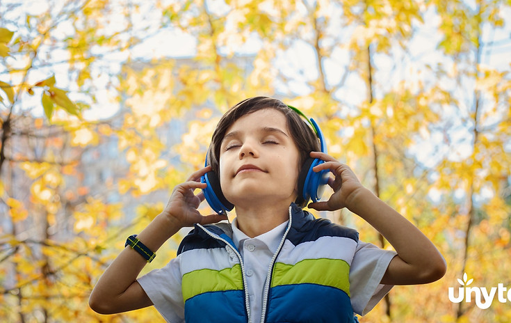 Child wearing blue headphones during Safe and Sound Protocol listening therapy, relaxed with eyes closed