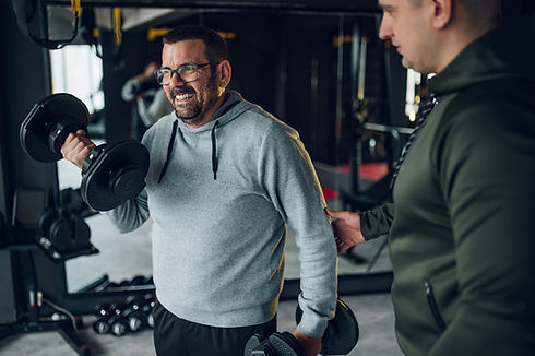 overweight man lifting dumbbells as part of a tailored personal training program for all fitness levels