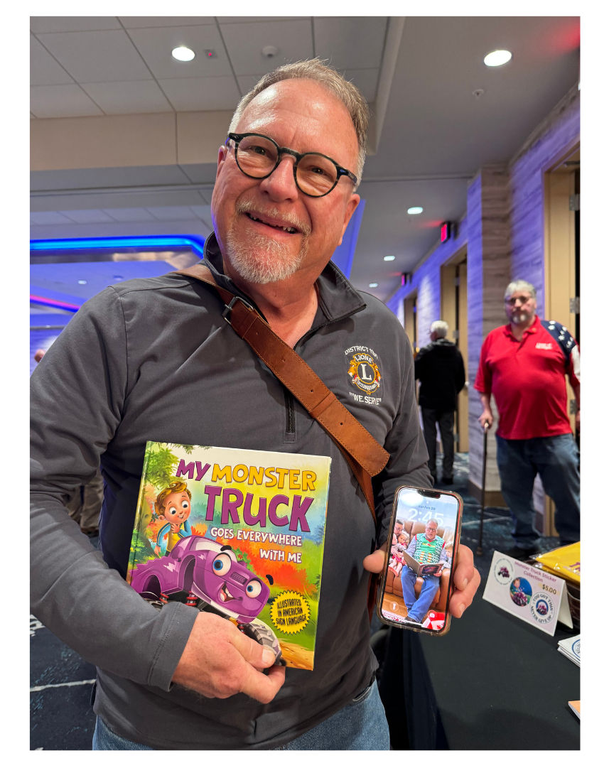 Grandfather at the 2026 Michigan Lions Forum holding “My Monster Truck Goes Everywhere with Me” and sharing his weekly reading tradition with his grandchildren.