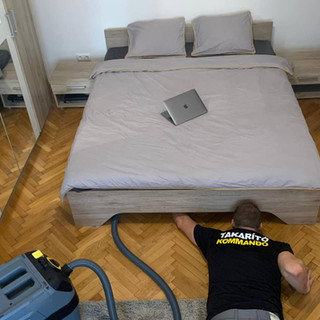 A Takarító Kommandó munkatársa az ágy alatti részt porszívózza
