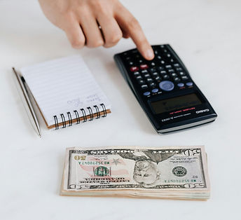 Accountant using calculator near pile of American dollars