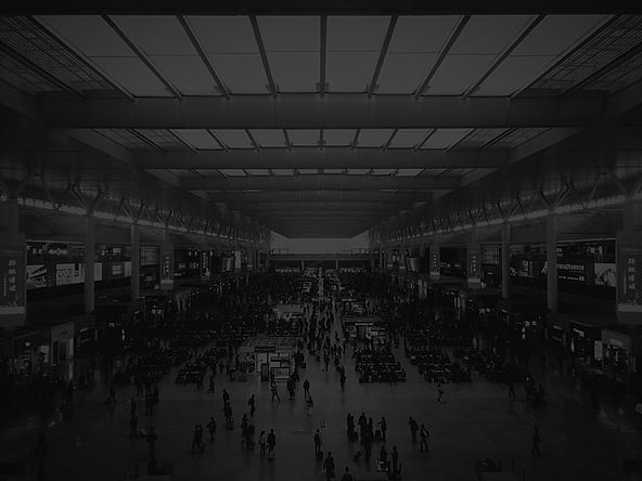Spacious Convention Center Hall With Large Skylights, Crowds Of Visitors, Exhibition Booths, And Digital Displays In A Black And White Scene