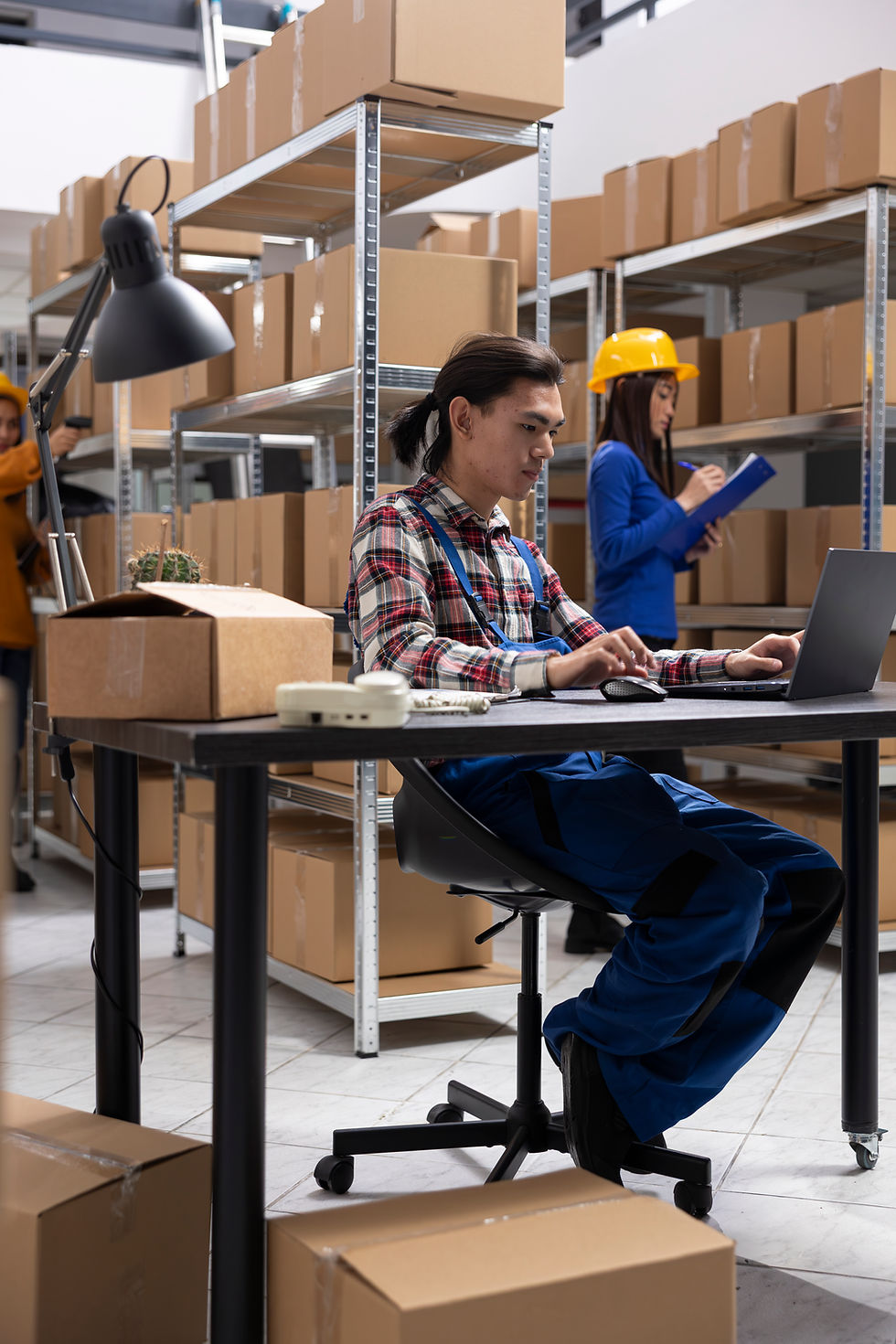 Warehouse Workers Managing Inventory With Boxes And Laptop Workstation