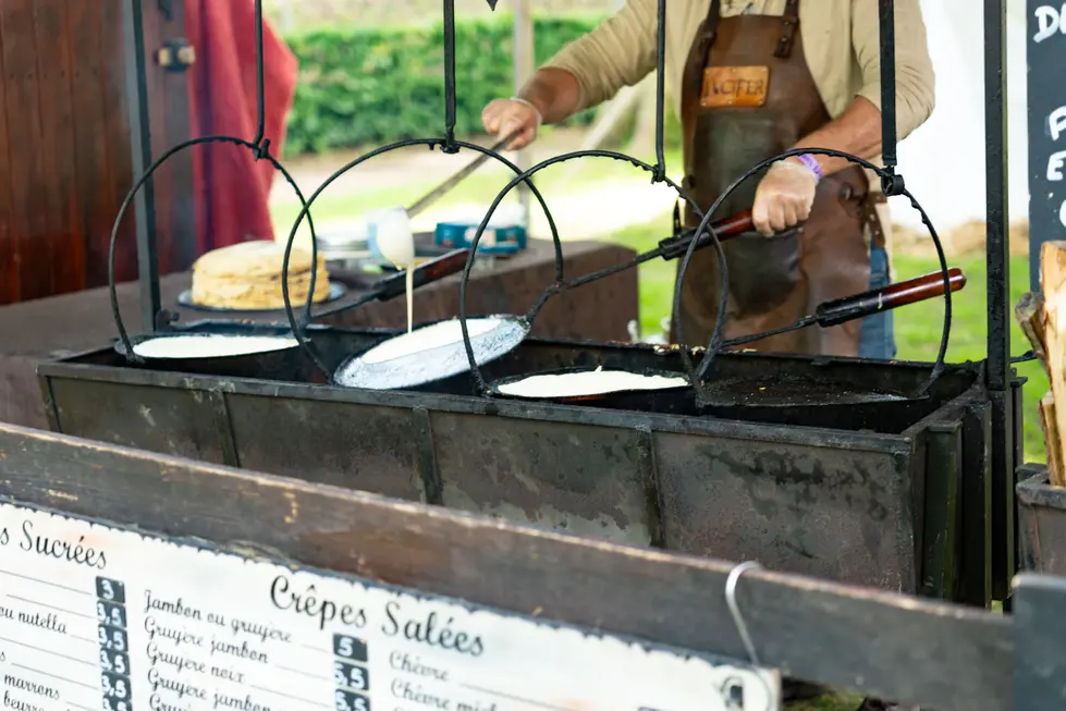 Stand de restauration historique préparant des crêpes traditionnelles sur des plaques de c
