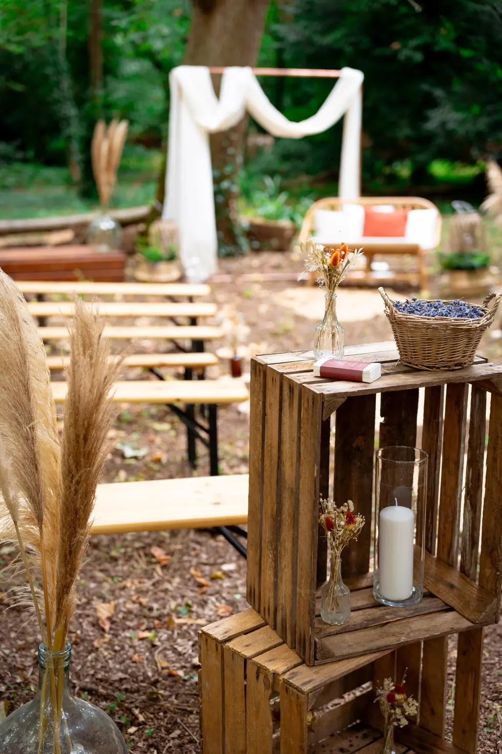 Décoration de cérémonie de mariage laïque en forêt avec bancs en bois, arche fleurie et pa