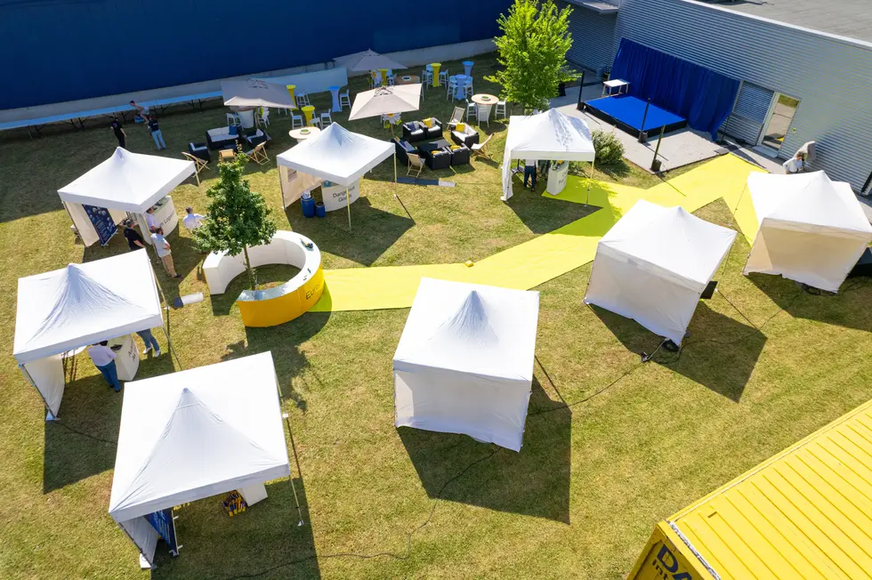 Vue de dessus d'un village de stands événementiels installé sur la pelouse d'un site logis
