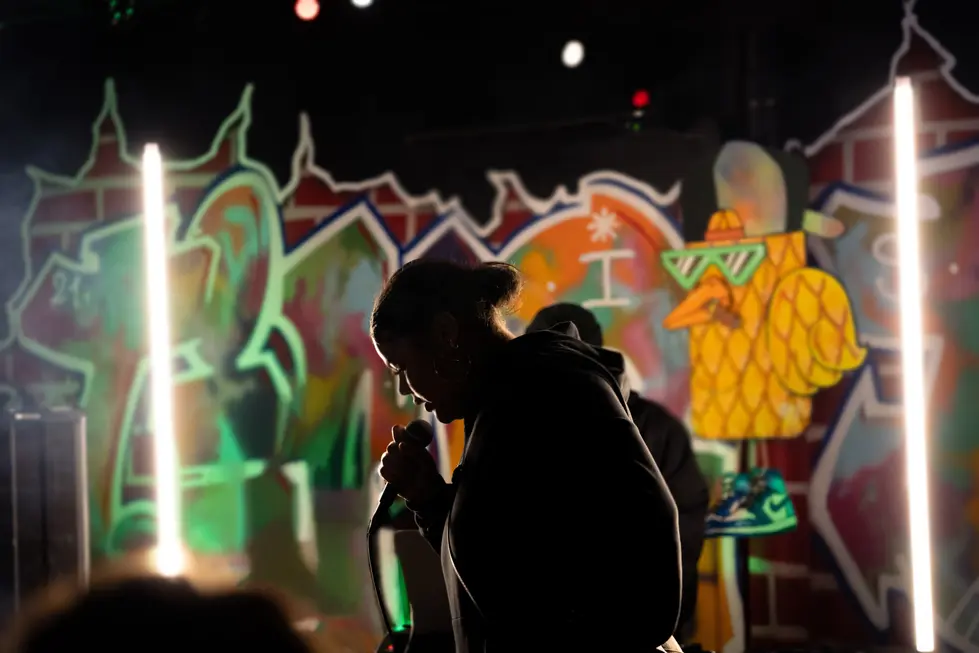 Performance de ZIENA sur scène avec éclairage néon et décor urbain.webp