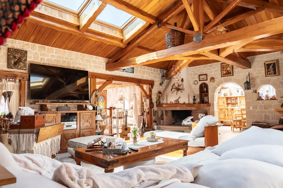 Salon rustique luxueux avec charpente en bois apparente, murs en pierre de taille et grand