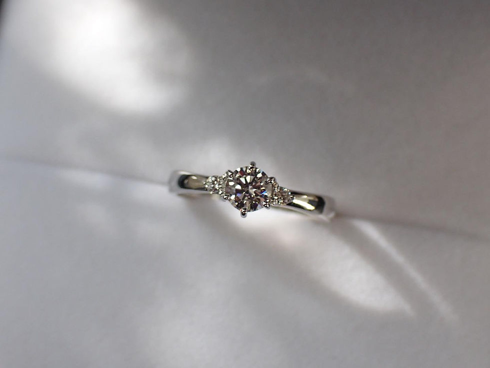 ダイヤモンドの両脇に小粒のダイヤモンドを留めたオリジナルデザインの鍛造製手作り婚約指輪
