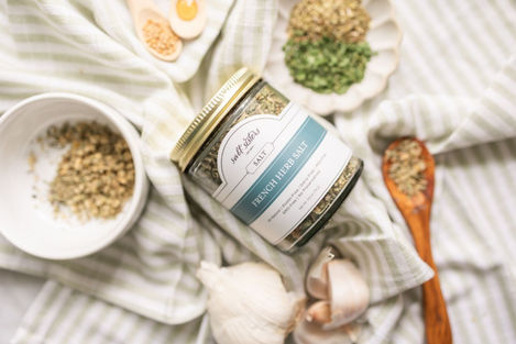 Salt Sisters infused salt jar surrounded by spices and garlic cloves.