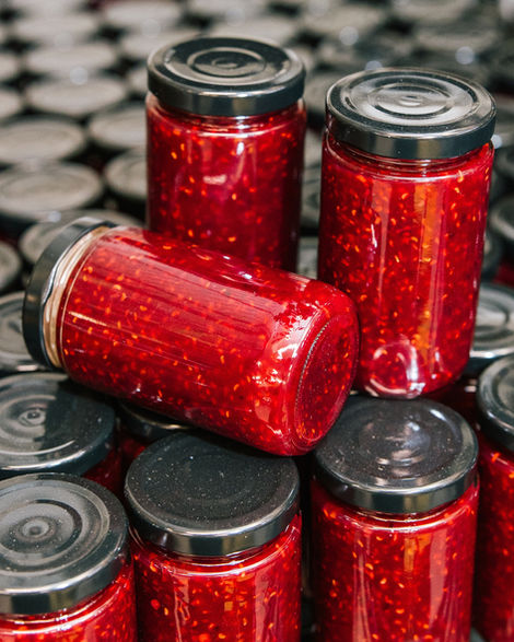 Jars of red jam stacked on other jars.