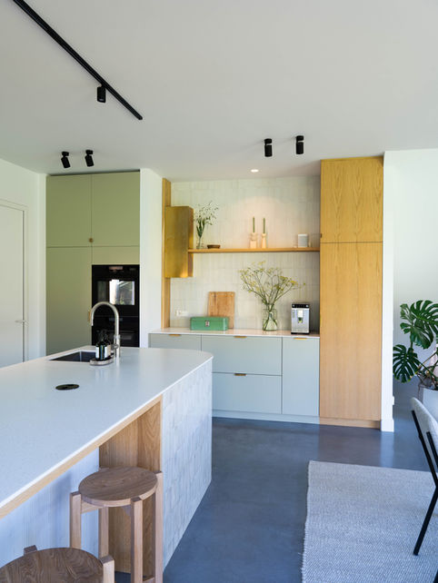 Maatwerk keuken en keukeneiland met ronde hoeken. Uitgevoerd in HI-MACS solid surface en eikenfineer en messing grepen.