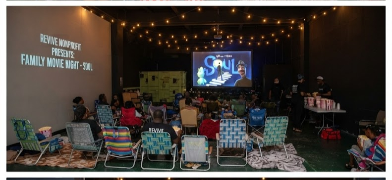 A large outdoor cinema screen glowing in a peaceful evening garden setup.