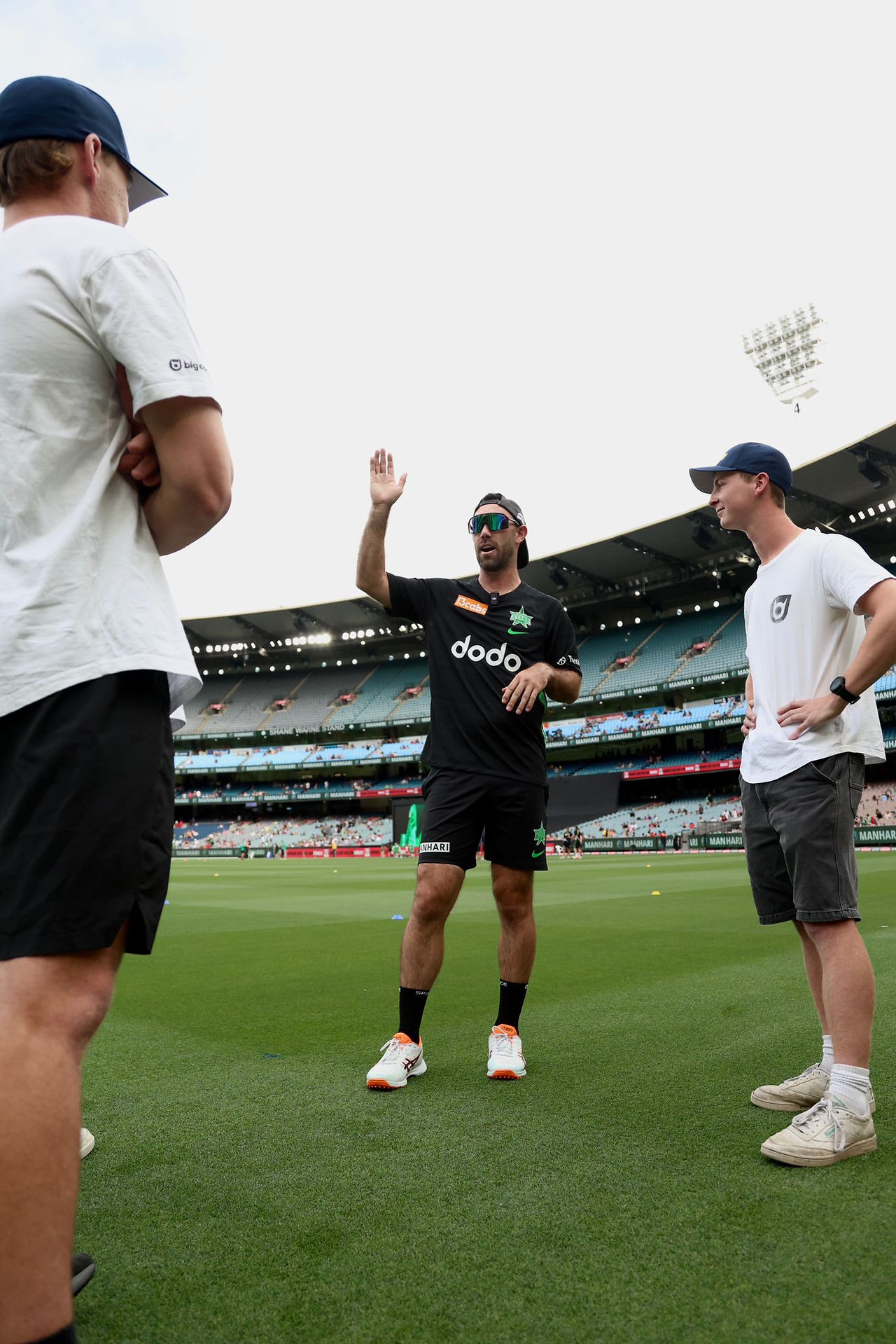 Two Catch Max online community members either side of Glenn Maxwell as he talks with one hand raised in the air.