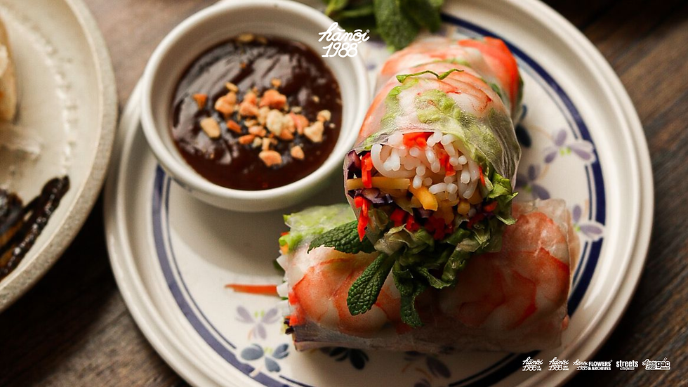 Fresh shrimp summer rolls on a floral plate with dark dipping sauce, garnished with herbs - a dish of Vietnamese cuisine