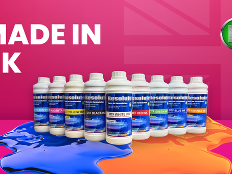 UK-made Resolute DTF ink bottles lined up on pink background with blue and orange ink splashes and bold MADE IN UK text.