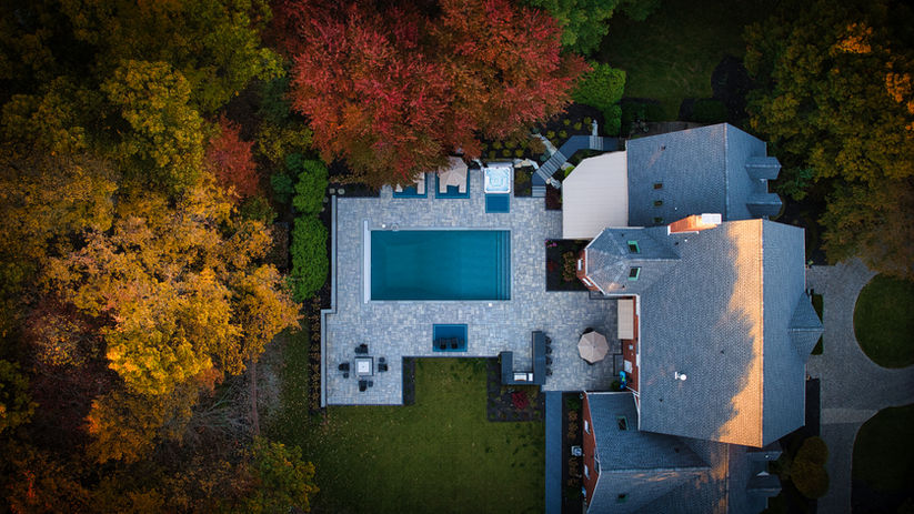 Aerial view of a house with a pool surrounded by autumn trees.
