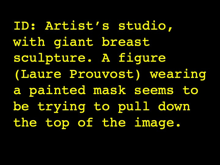 Artist’s studio, with giant breast sculpture. A figure (Laure Prouvost) wearing a painted mask seems to be trying to pull down the top of the image.