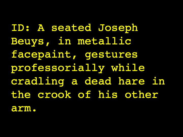 A seated Joseph Beuys, in metallic facepaint, gestures professorially while cradling a dead hare in the crook of his other arm