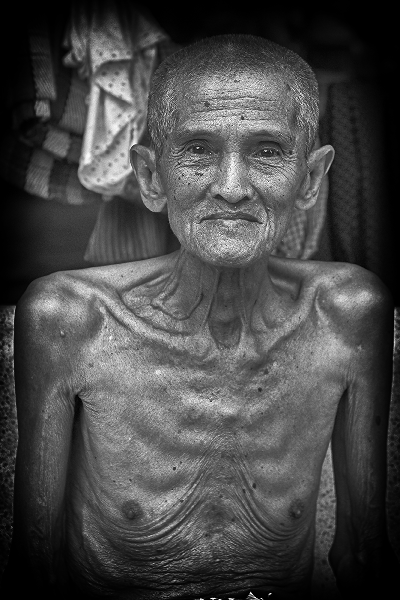 Black and white close-up of an elderly man with a kind smile, showcasing facial details and wisdom — an intimate study by Cristian Mitrani.