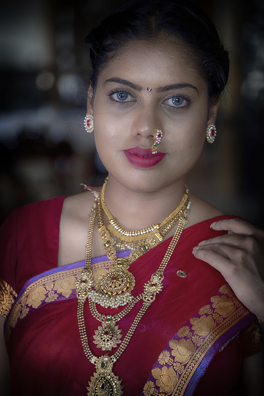 Portrait of a woman dressed in traditional Indian attire with intricate gold jewelry and a confident gaze — a vibrant cultural capture by Cristian Mitrani.