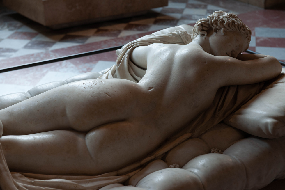 Detailed close-up of a reclining nude marble sculpture, showing the back and curves with soft natural light — a classical artwork by Cristian Mitrani.