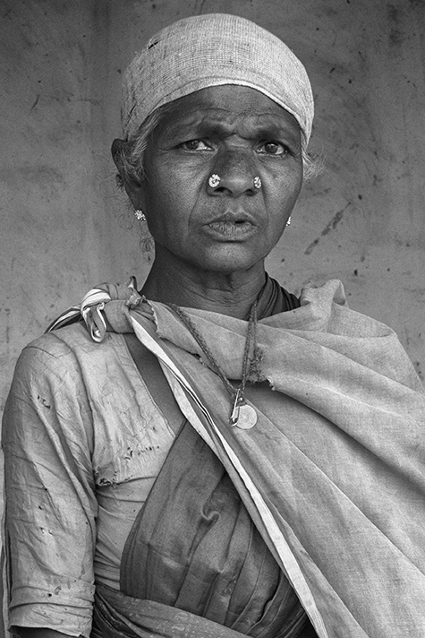 Black and white portrait of an elderly woman wearing a headscarf and traditional clothing, her expression solemn and dignified — a respectful cultural study by Cristian Mitrani.