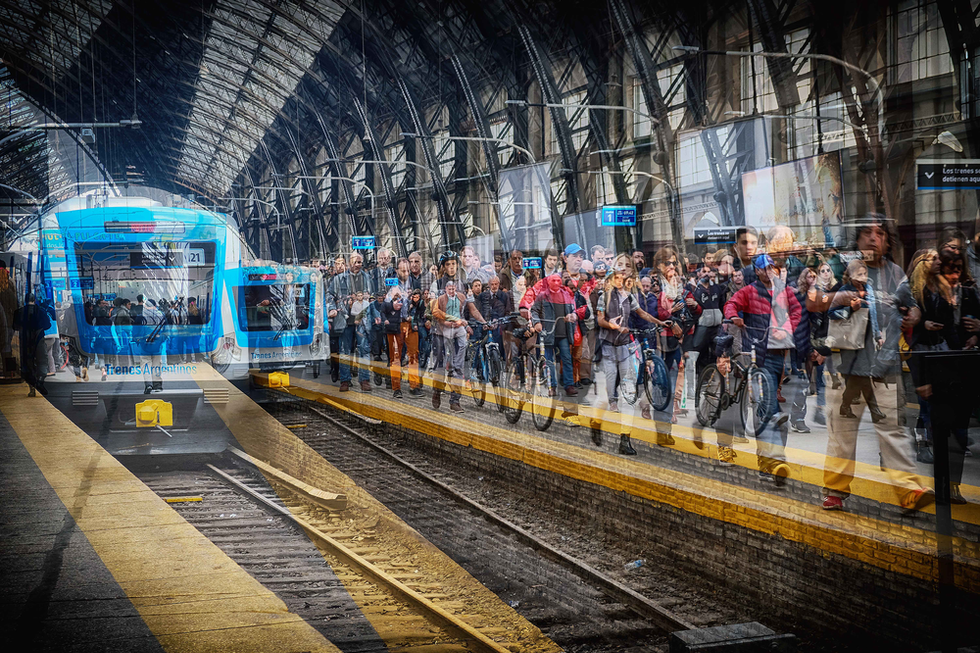 Layered image of a bustling train station platform with arriving blue train and overlapping figures in motion — a dynamic urban scene by Cristian Mitrani.