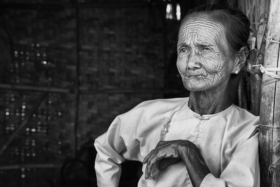 Black and white portrait of an elderly woman with deeply etched facial wrinkles, sitting thoughtfully with a serene expression — a powerful cultural study by Cristian Mitrani.