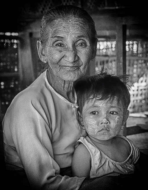 Black and white photo of an elderly woman holding a child, both looking thoughtfully at the camera — a heartfelt family portrait by Cristian Mitrani.