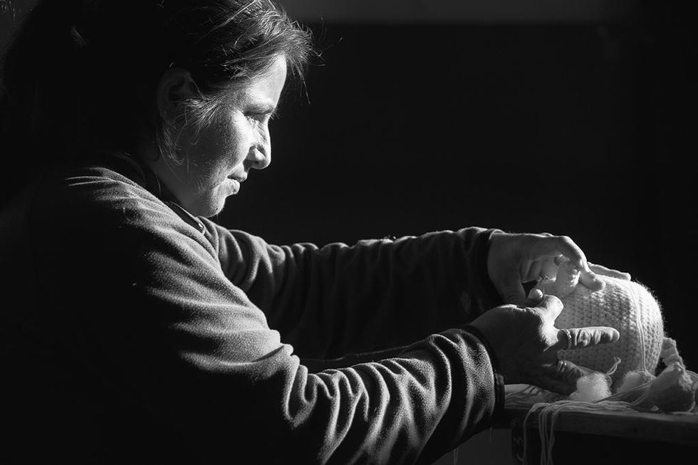 Black and white portrait of a woman focused on delicate handwork, illuminated by soft light — a tribute to craftsmanship by Cristian Mitrani.