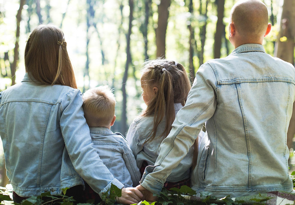 husband and wife holding hands with two children seated between them