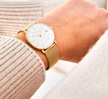 Nahaufnahme einer goldenen Damenuhr der Marke Junghans mit Milanaise-Armband, getragen zum beigen Pullover, Lifestyle-Fotografie Yannik Planta