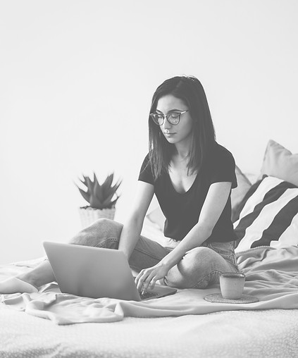 A photo of a woman on a bed with a laptop, in a virtual therapy session