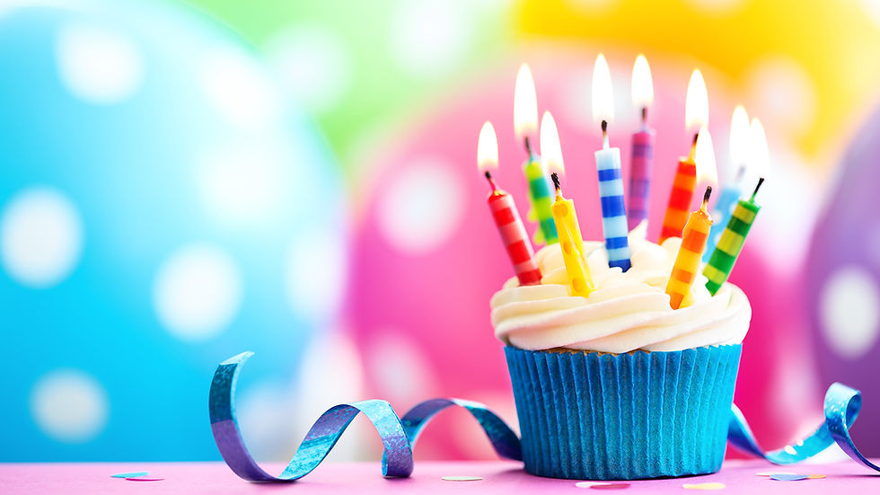 Chocolate cupcake with a ruffled wrapper and lit candle, frosting piled high