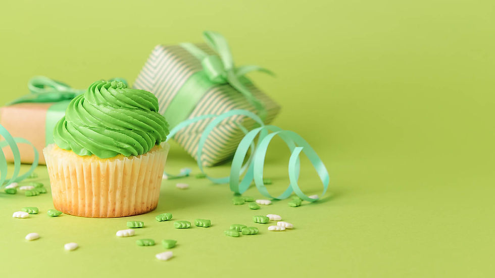Cupcake with a ruffled wrapper, frosting piled high and a lit birthday candle