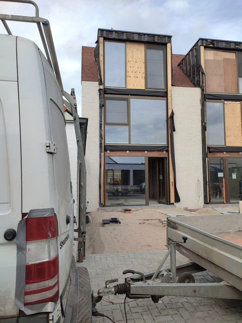 Bouwplaats met onafgewerkte gebouwen en een voertuig op de voorgrond.
