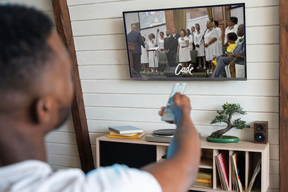 A man sitting in front of a TV watching a choir.