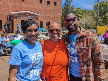 A husband and wife embracing another woman for a photo.