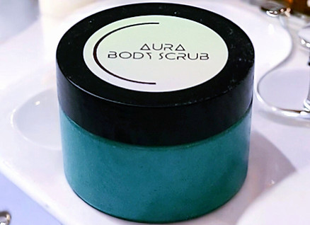 Aura Moisturizing Body Scrub displayed on bathroom countertop.