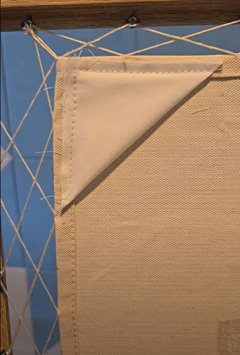 Back of the frame showing how the thread is strung between the towel and screws.