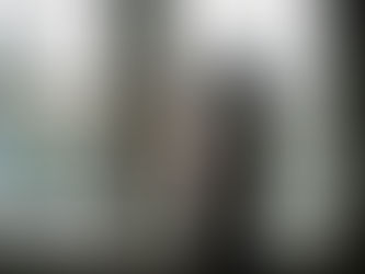 אישה עומדת ליד חלון בביתה ומתבוננת החוצה לרחוב מגורים בריטי, רגע של בדידות פנימית והסתגלות רגשית ברילוקיישן