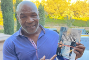  A cheerful man displays a book, smiling broadly as he holds it up.