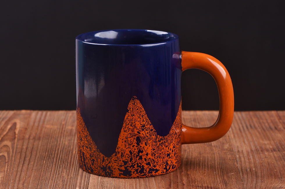 Blue rhino skin Chinese lacquer mug with an orange mountain pattern and orange handle on a wooden table