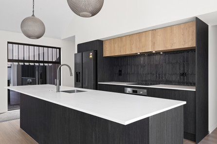 Sleek black kitchen with wood cabinetry by Hedgley Corporation, designed by Kian Clements-Ormond with minimalist elegance