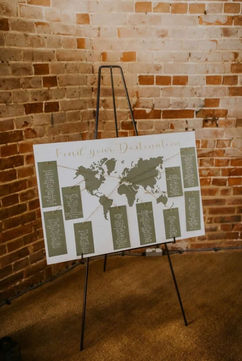 Wedding table plan showing a map of the world in sage green on a white background with gold calligraphy details